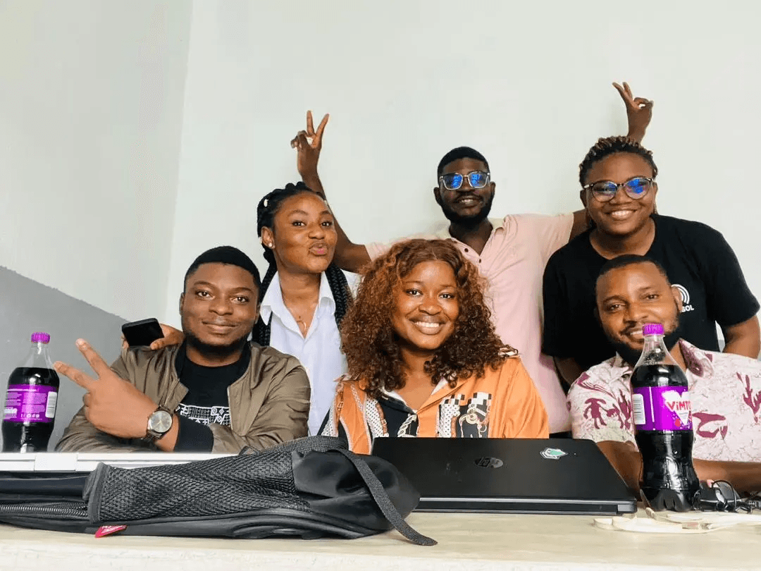 Nkwa team in a meeting, smiling and giving peace signs